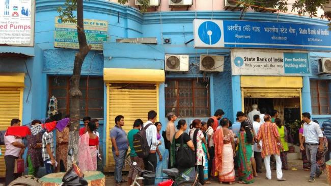 People stand in queue to exchange currency notes