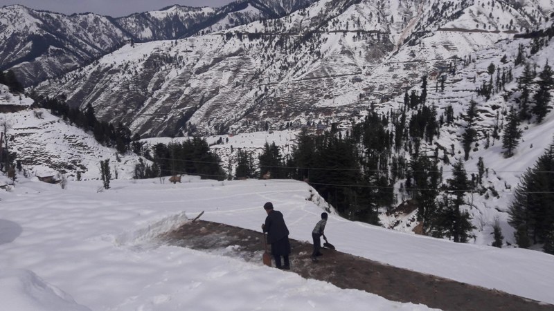 People walk through snow covered Bhaderwah-Chamba inter-state road in Kashmir