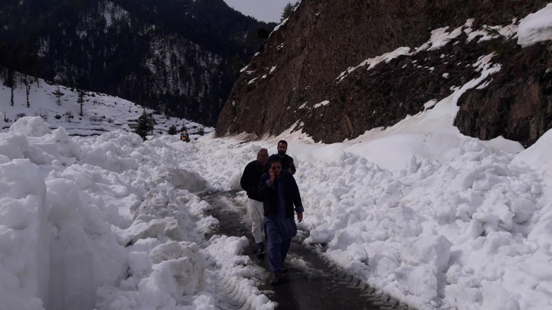 People walk through snow covered Bhaderwah-Chamba inter-state road in Kashmir