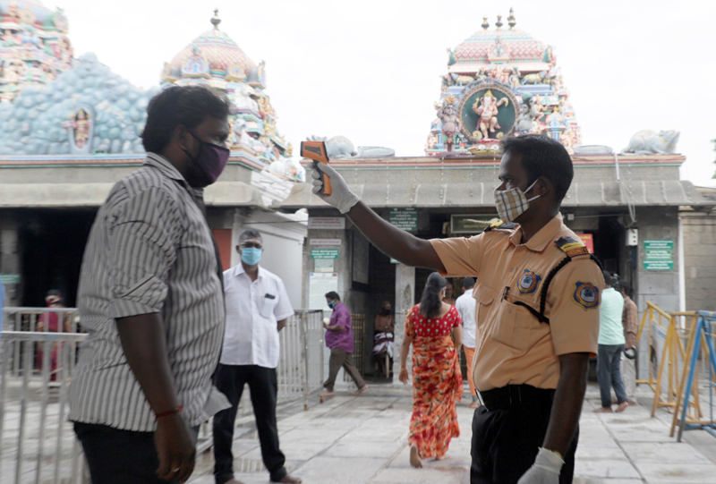 A security personnel monitor body temprature of a devotee before entering into Kapaleeswarar Temple