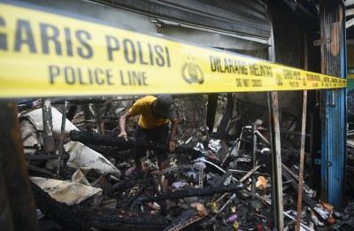 Indonesia: A resident looks for his belongings from a charred house