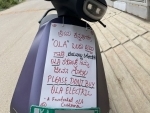 Ola scooter user places a placard on vehicle to urge people not to buy it