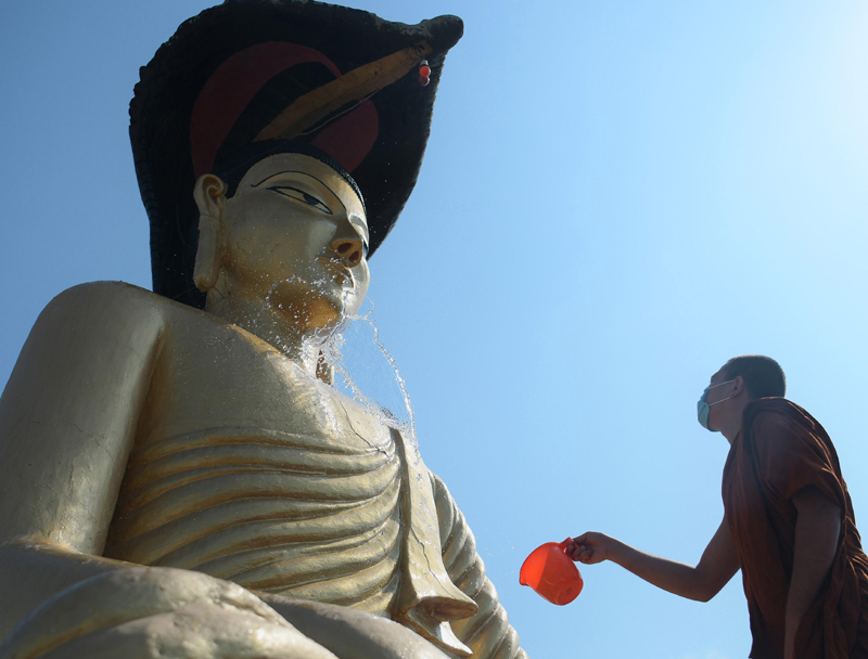 Buddhist monk cleaning statue of Lord Buddha at Agartala monastery