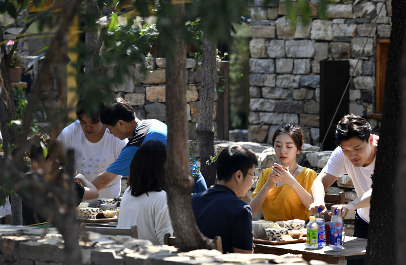 Tourists rest in a yard of a homestay in Xijingyu Village