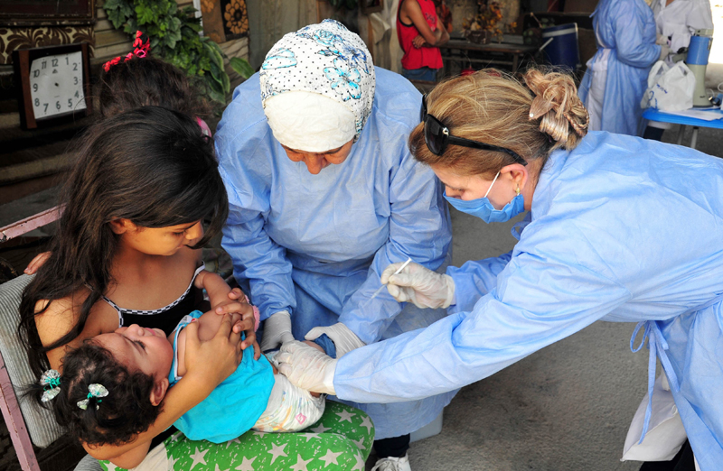 Syria: Medical workers give a vaccine to a child