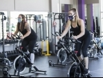 People wearing face masks exercise at a reopened fitness club in Barrie