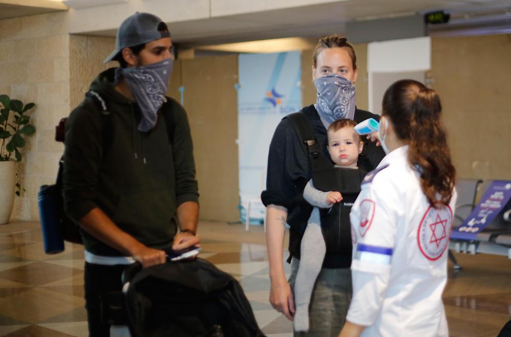 Israeli medical worker checks temperature passengers