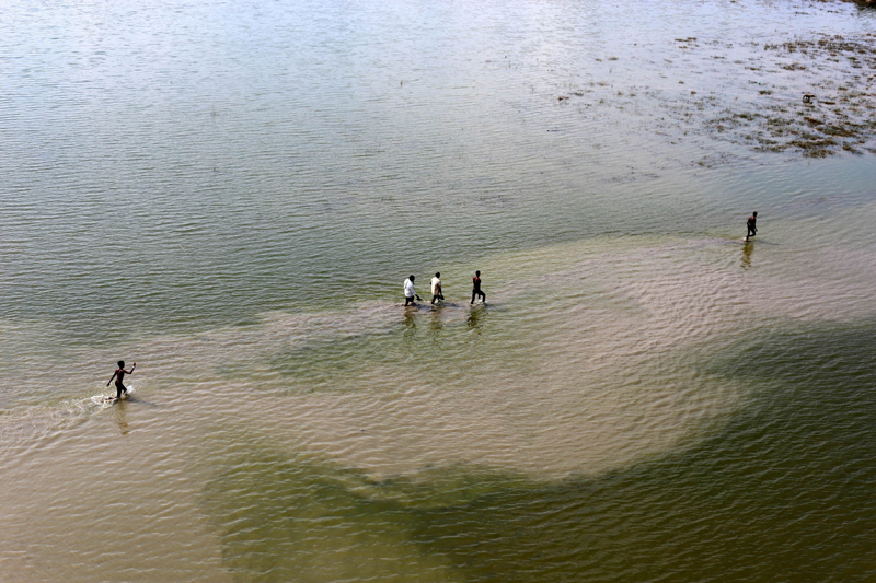 Prayagraj: Devotees walk in flood water mud on the river bank of Ganga