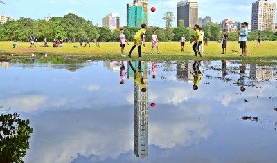 Boys play football in Kolkata's rain-washed urban park